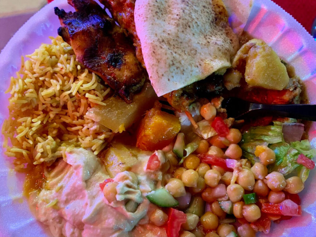 A plate of Rice, hummus, shawarma, dates, and more