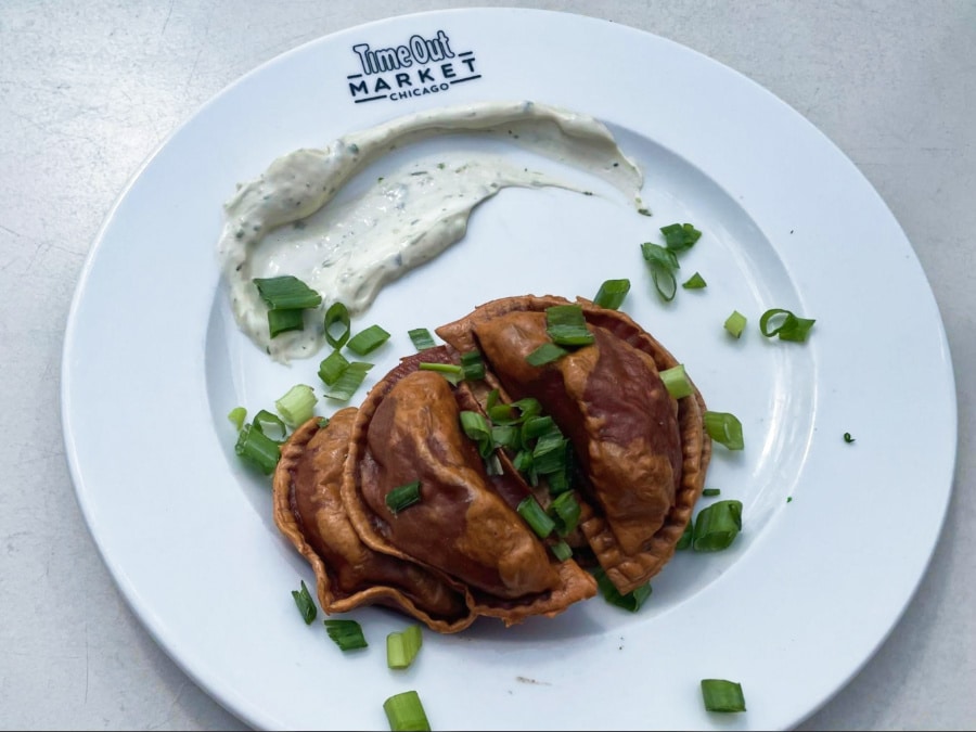 A plate of Emparogis with white sauce on the side and topped with sliced spring onions from Polombia