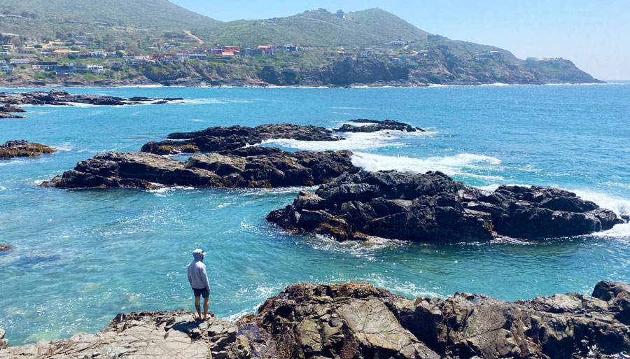 View of a man looking at the rocky coastline