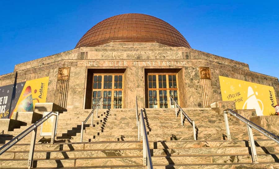 Exterior and entrance view of Adler Planetarium with a clear blue sky in the background
