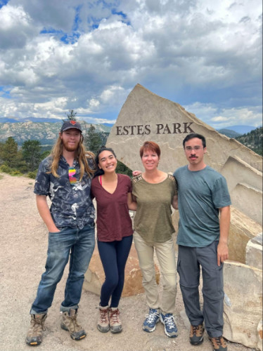 Travel Lemming editor, Abigail Bliss with her family at the entrance sign in Estes Park