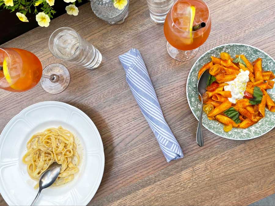 View of pasta with cherry tomatoes and burrata with drinks in Etta