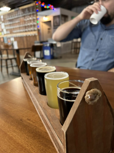 A man drinking his beer and a flight of beer at the table in Everett’s At Large Brewing