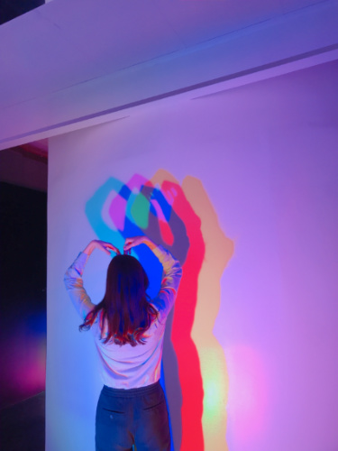 A woman posing with three color LED lights at WNDR museum