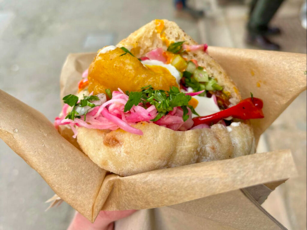 Holding a falafel pita sandwich with fresh vegetables on it