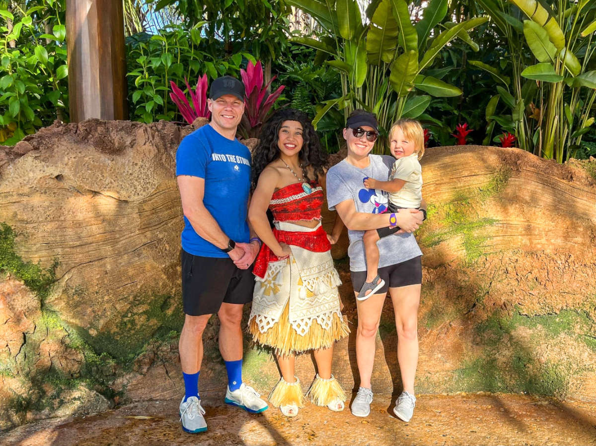 The author Katie Neufeld and her family, posing for a photo with the character of Moana