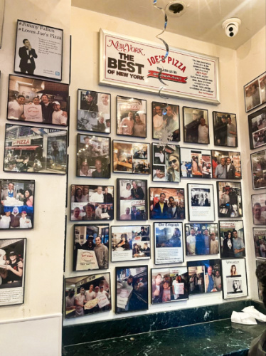 view of the portraits of the famous patrons on the wall of Joe’s Pizza
