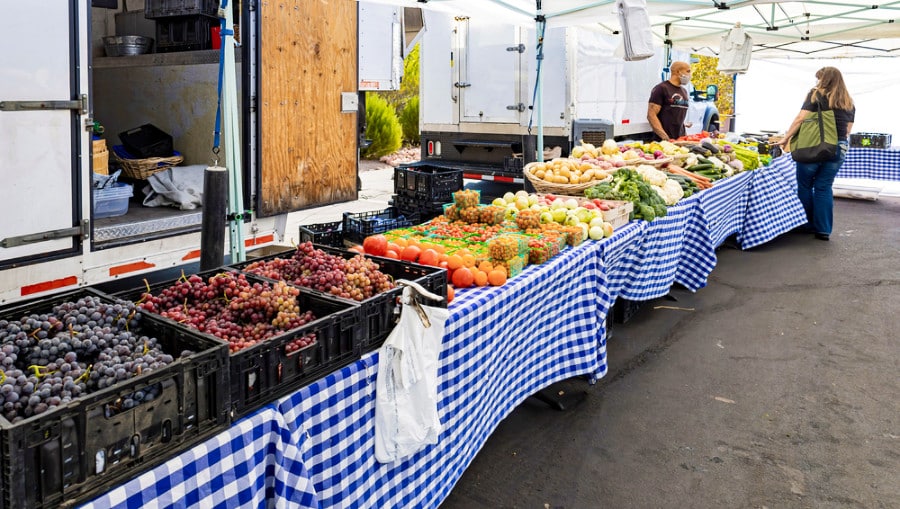 A vendor selling fruits and vegetables in a booth in Farmers Market