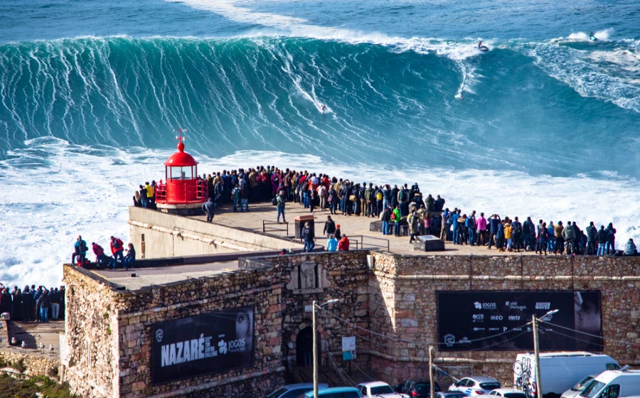 Tourists watching the big waves from the bright red lighthouse of Nazare