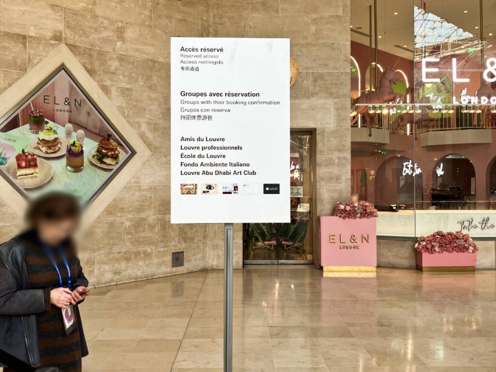 A woman near the signage of the fast-track access in Louvre