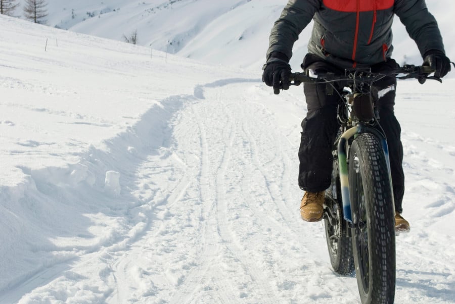 A man fat biking on the snow covered road