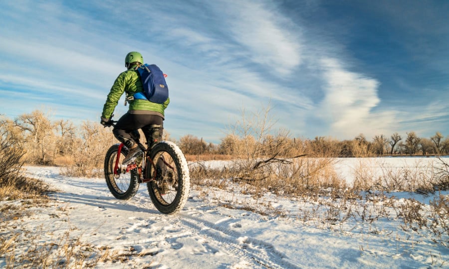 A man riding a fat mountain bike in winter