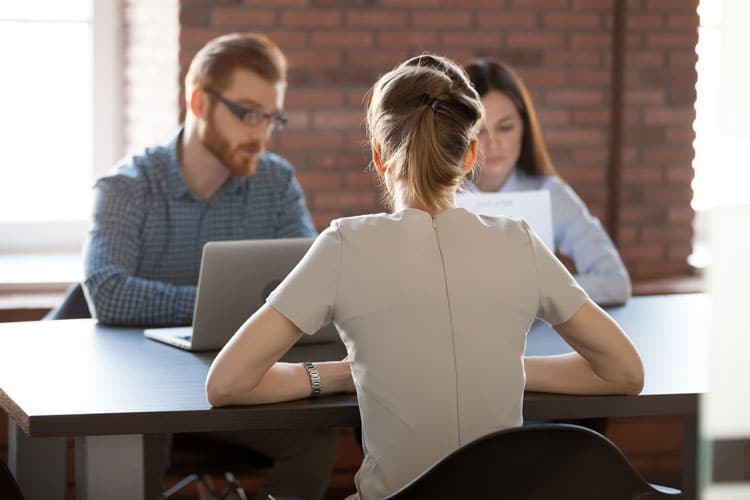 Woman in front of a guy with laptop and woman with paper
