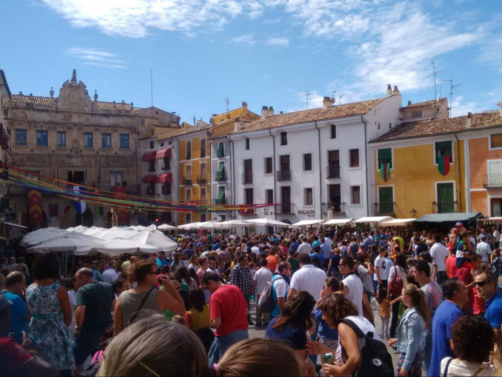 A bustling square in Cuenca, Spain during a festival, filled with people