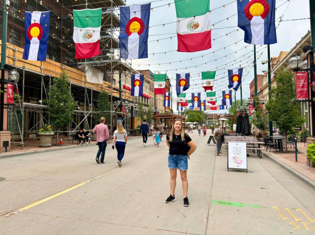 Author Laura Falin stands in Larimer Square, surrounded by buildings adorned with flags