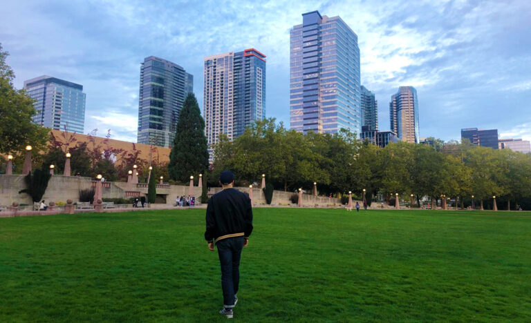 View of a man walking on the grass field in Bellevue surrounded by skyscrapers