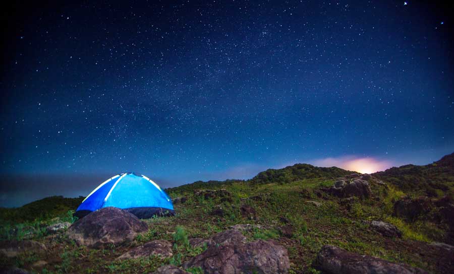 A camping tent and the stars in the sky above it
