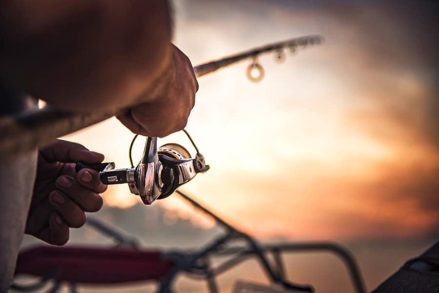 A closeup look at a man's hands holding a fishing rod during sunrise