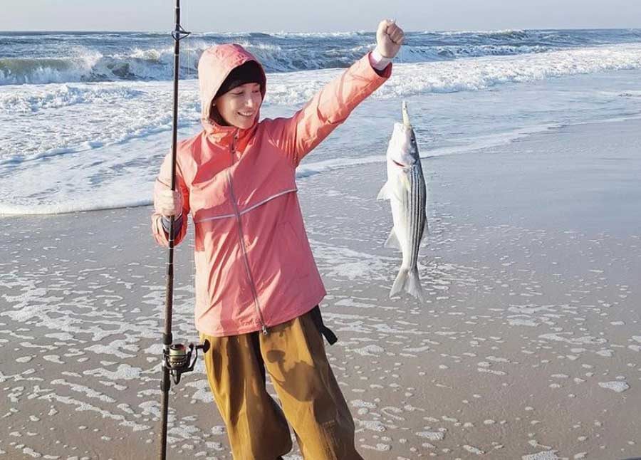 The author holding a fishing road and a fish that she caught in Long Island