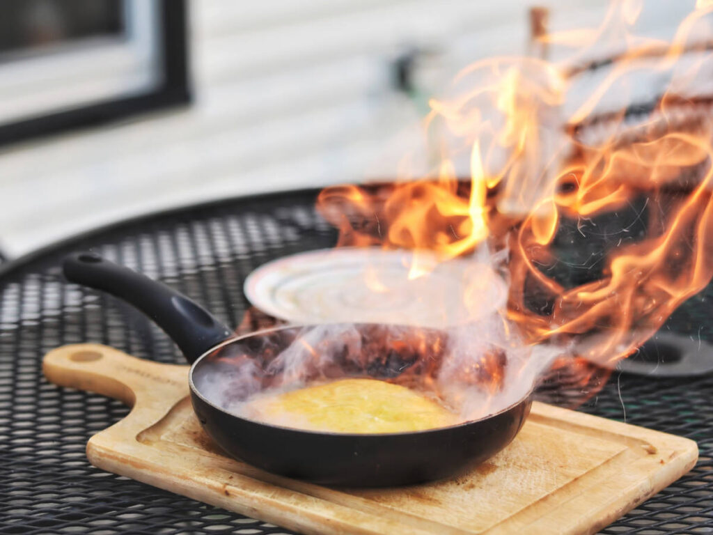 A Flaming saganaki on top of a wooden board