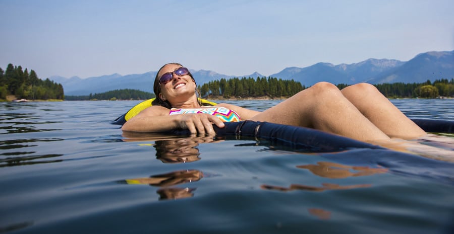 A woman relaxing under the sun while floating in the lake.