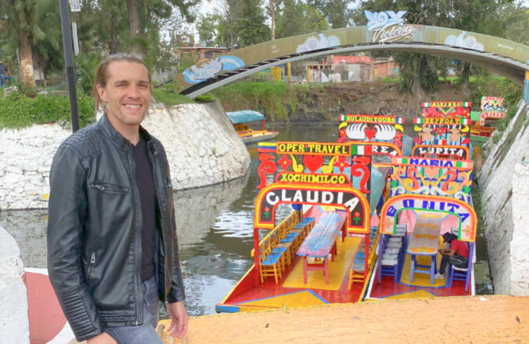 The author Nate in front of colorful boats at Floating Gardens of Xochimilco