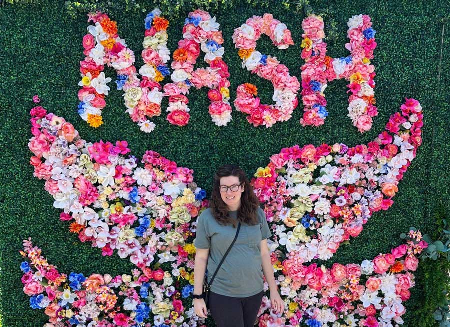 The author smiling for a photo with a flower decorations on her background