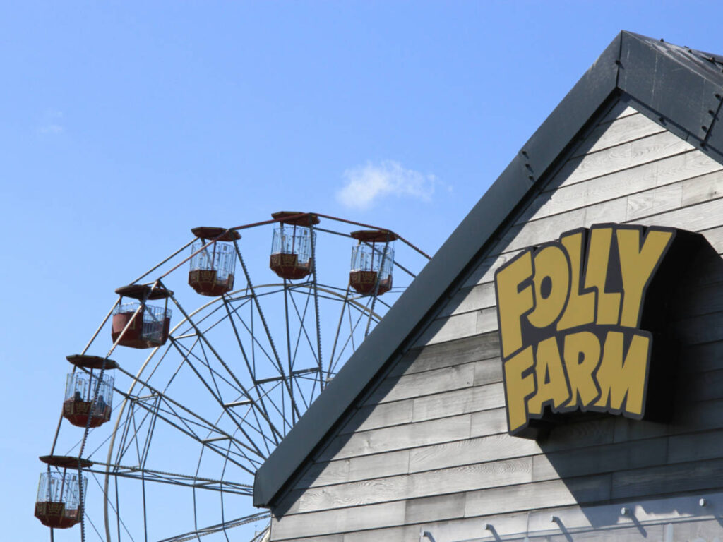 View of the Ferris wheel behind the building with a logo of Folly Farm