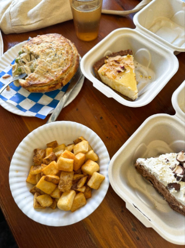 Variety of food and desserts on a wooden table at Bang Bang Pie & Biscuits