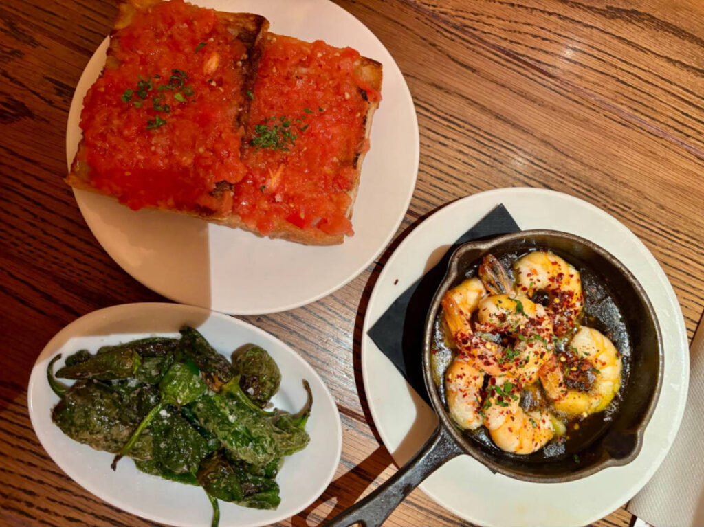 Pan con tomate, padrón peppers, king prawns with garlic, chili and olive oil on the table