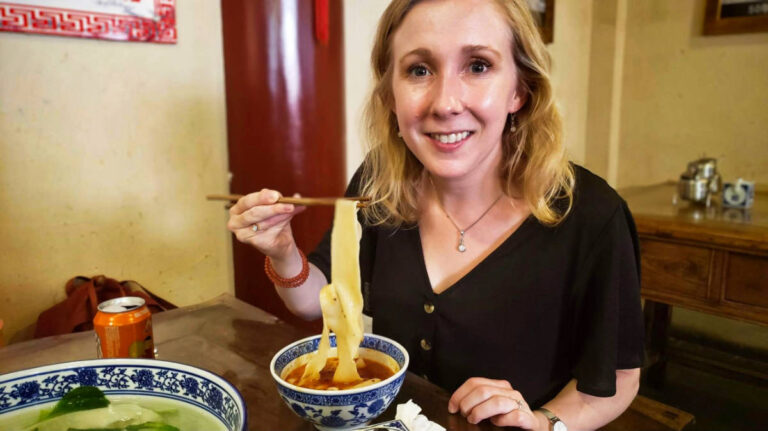The author Sarah Heath, eating a long and thick noodles in Xi’an, Foodie Adventure in China