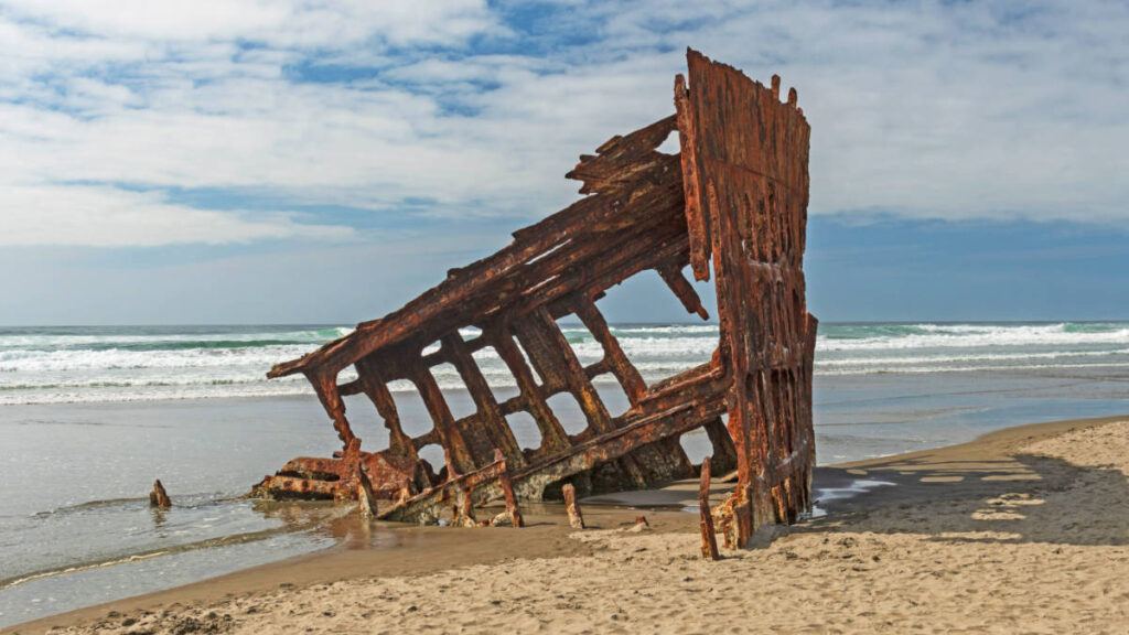 A rusted shipwreck on the shoreline of Fort Stevens beach