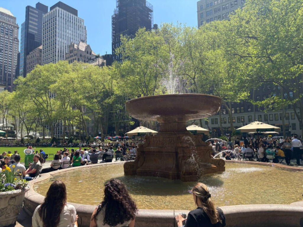 People relax and enjoy the sunshine around the fountain in Bryant Park