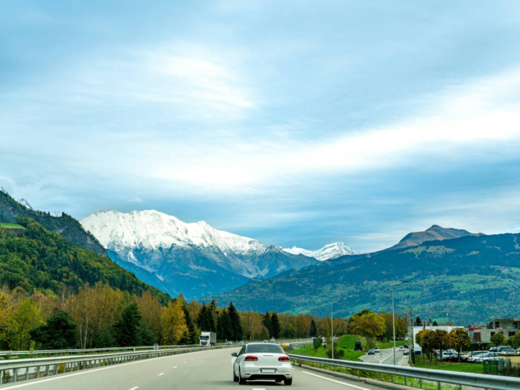 A car driving along the French highway with a scenic view of the Alps