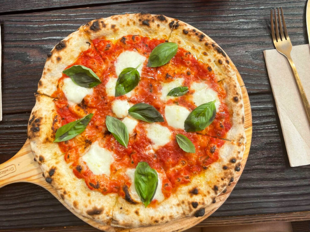 Closeup look of the pizza on the serving board with fork and knife on the side