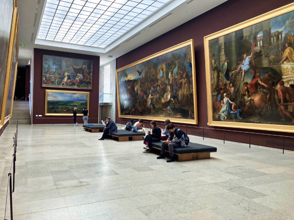The people sitting at the second-floor gallery at the Louvre