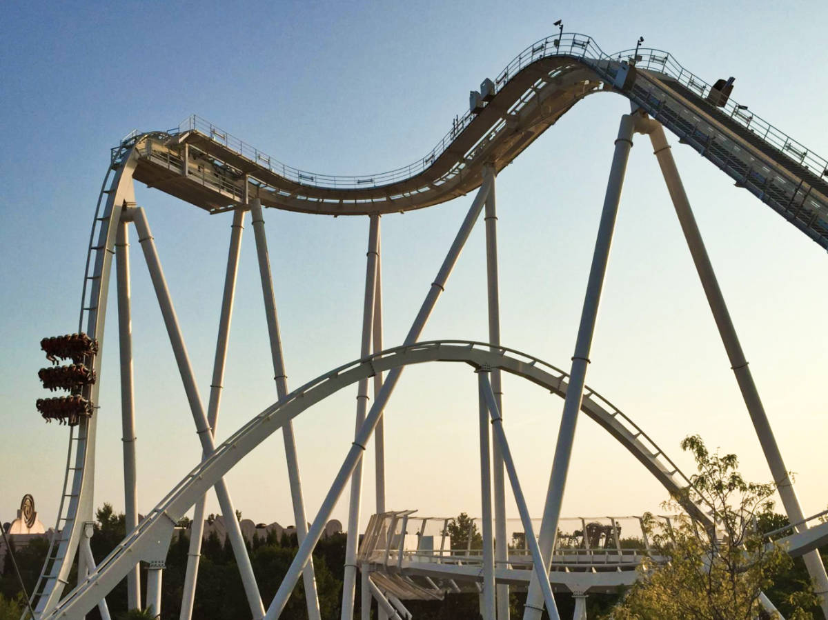 The roller coaster at Gardaland Park, twisting and turning with excited riders against a clear blue sky