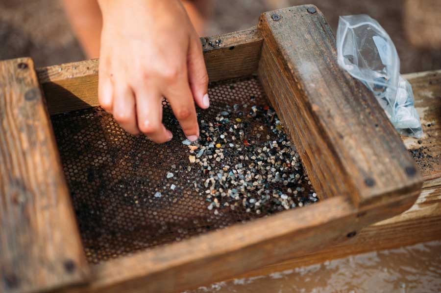 Kid's hand using a sifter on sand