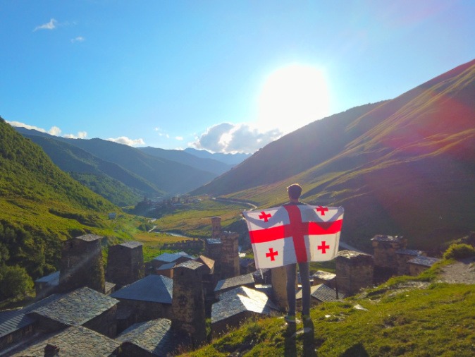 The author Nate Hake with the flag of Georgia, looking out over Ushguli