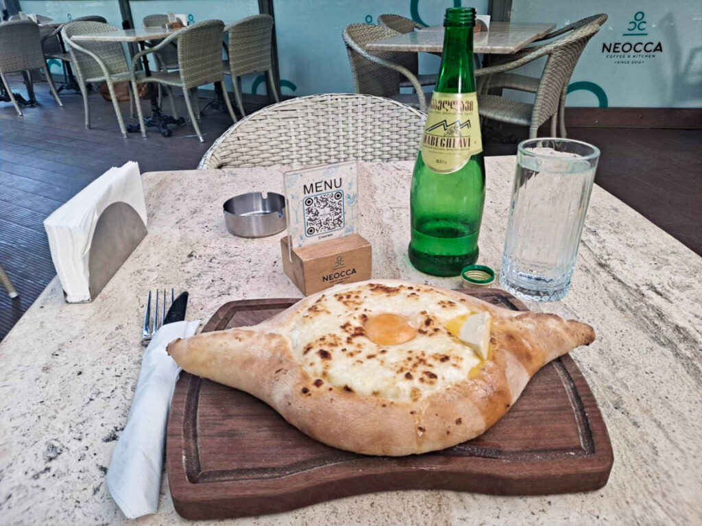 Khachapuri on the wooden board and a bottle of wine