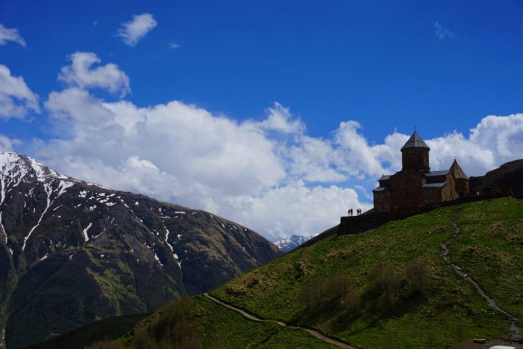 A church on a hill with a stunning view of a mountain range in the background