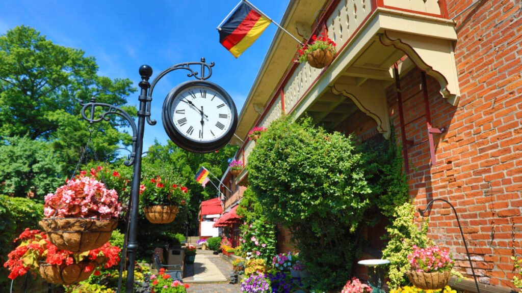 A clock and a flag of Germany at a colorful garden in the German Village