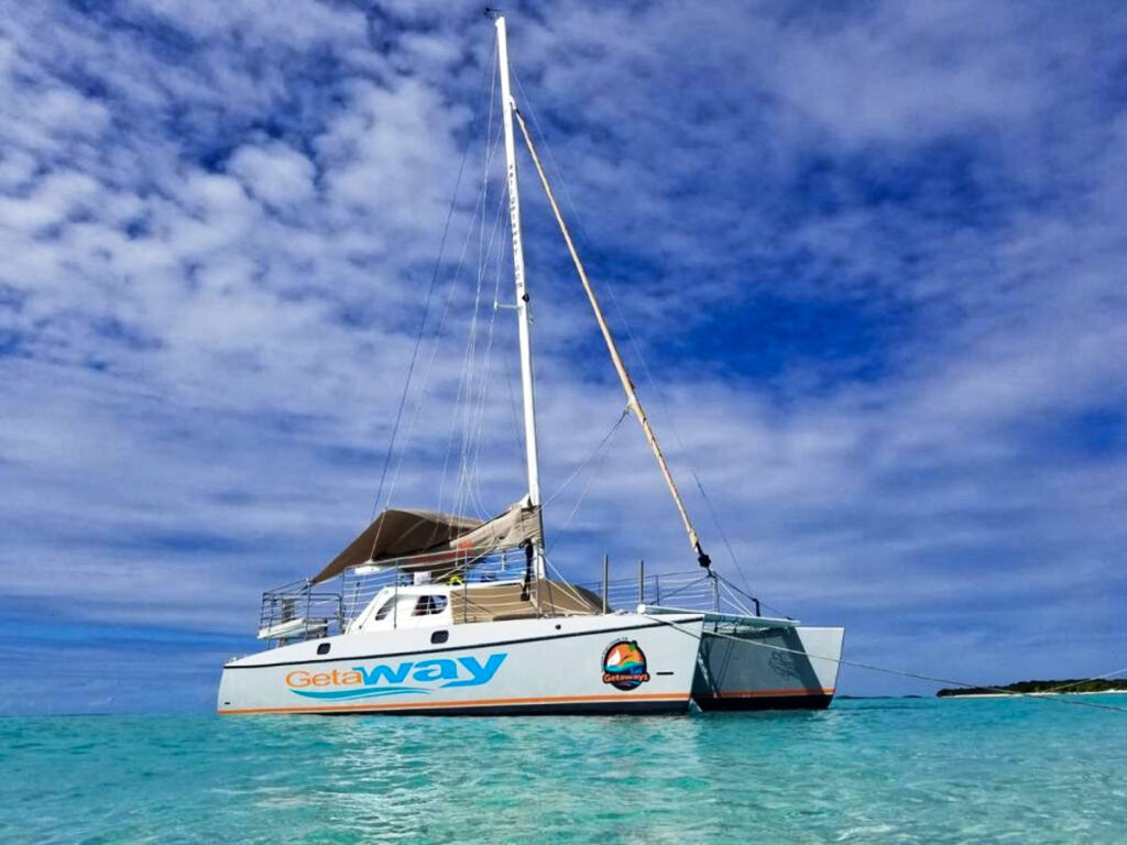 A white Getaway catamaran sailing on the turquoise blue water