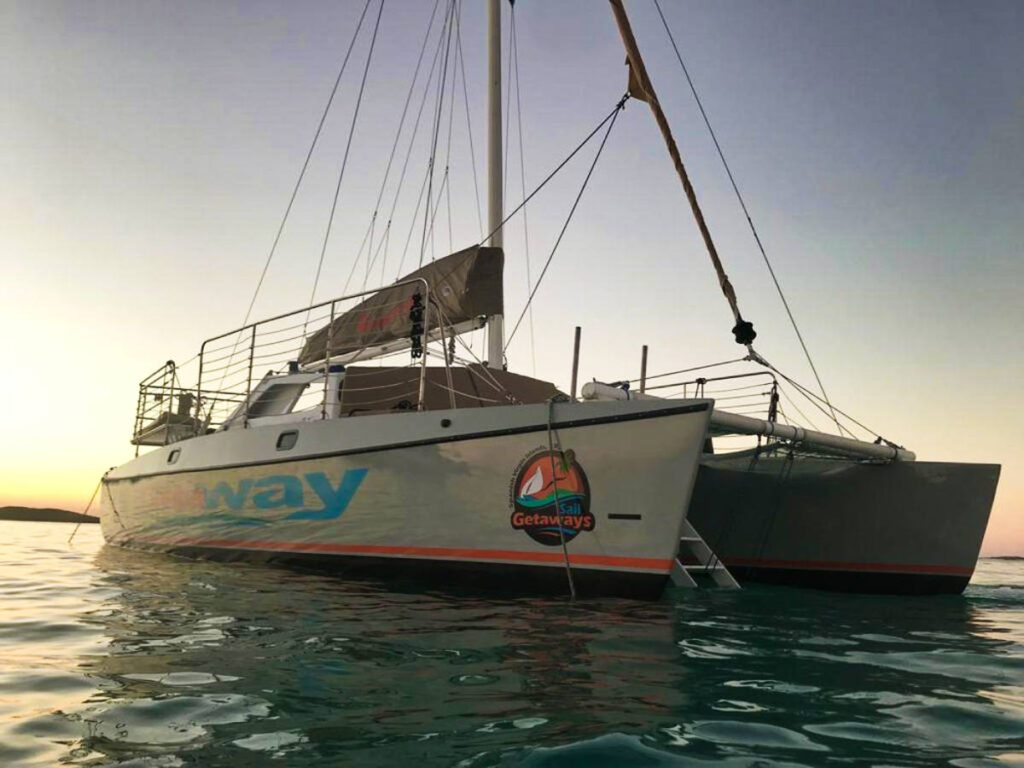 A white Getaway catamaran sailing at sunset