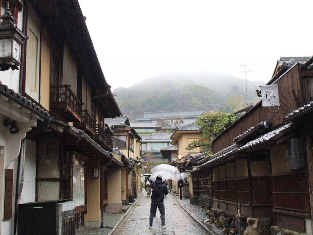 The people taking photos in the middle of a street in Gion neighborhood on a rainy day