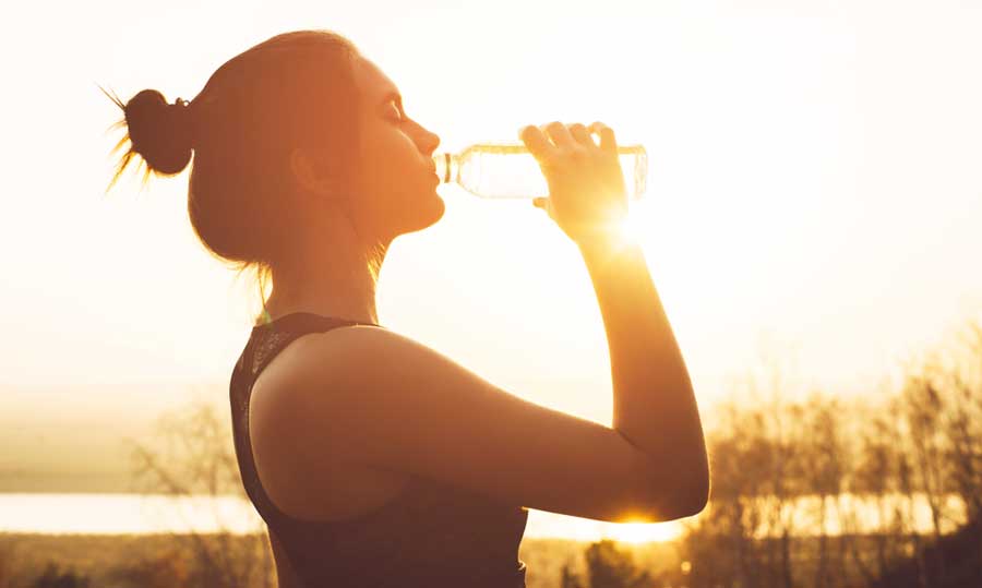 A woman drinking her water during sunrise