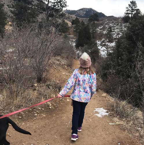 The author's daughter holding their dog leash during a winter hike