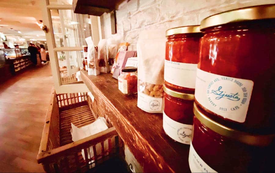 Bottles of hors-d’œuvre spread and nuts in a pack displayed on a shelf in Gjusta