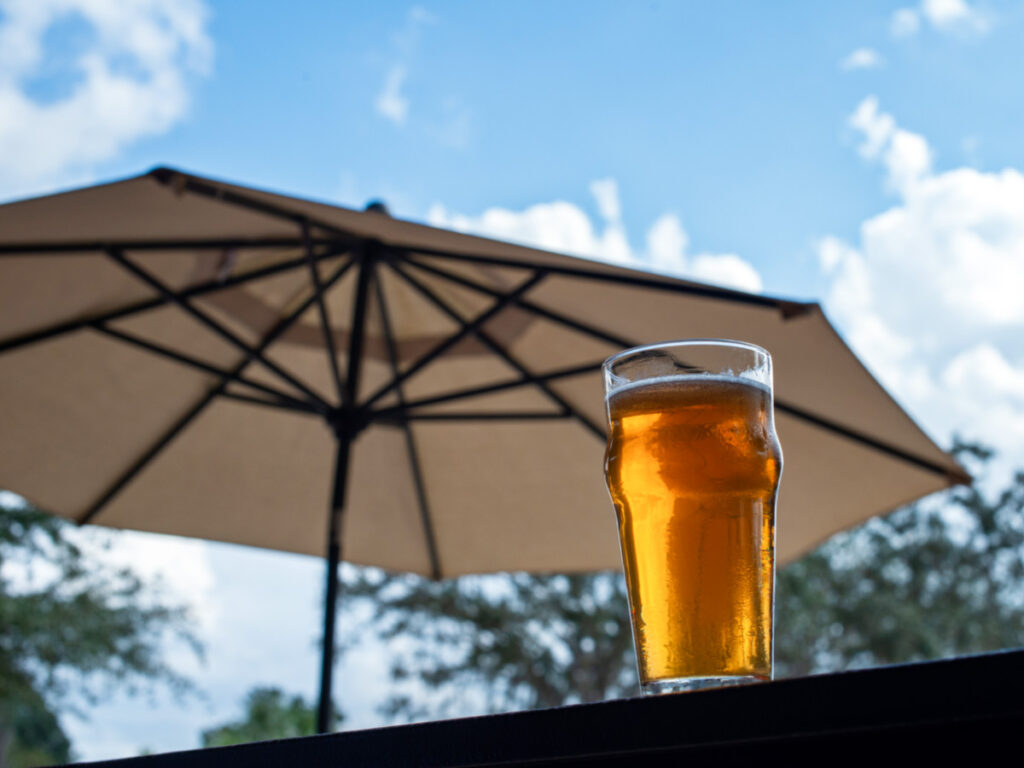 A pint of beer at the outside seating area with an umbrella in the background