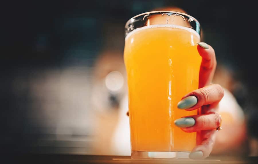 View of a woman's hand holding a glass of beer